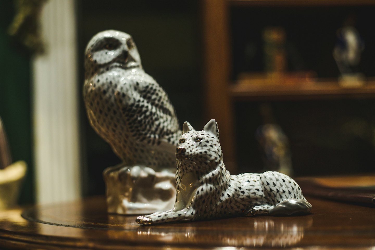 Ceramiczne figurki sowy i lisa na ciemnym drewnianym blacie.