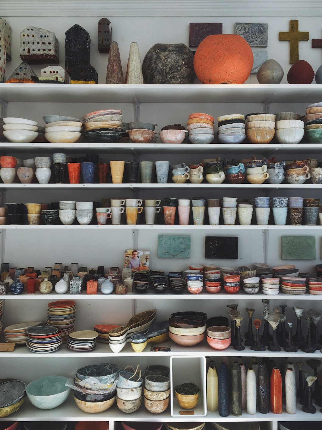 Półki wypełnione różnorodną, ręcznie robioną ceramiką.